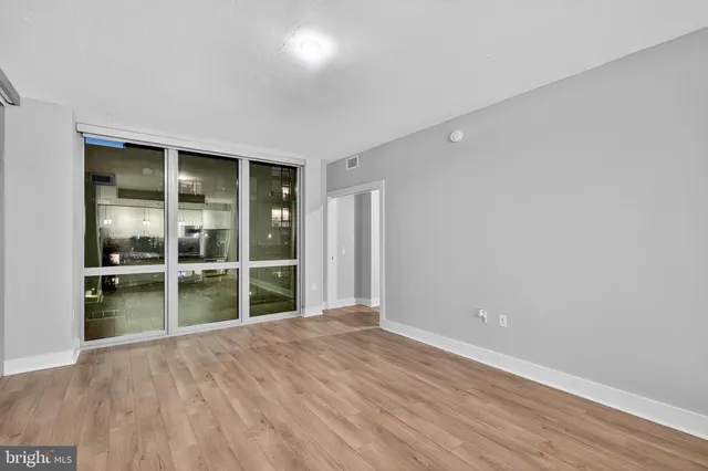 an empty room with wooden floor and windows