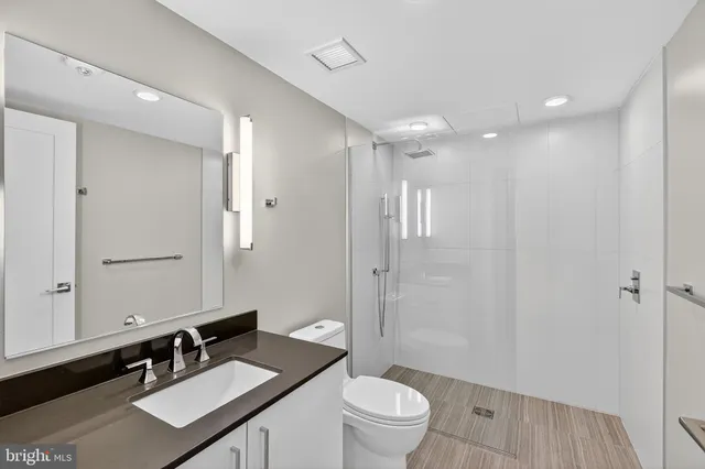 a bathroom with a sink a toilet a mirror and shower