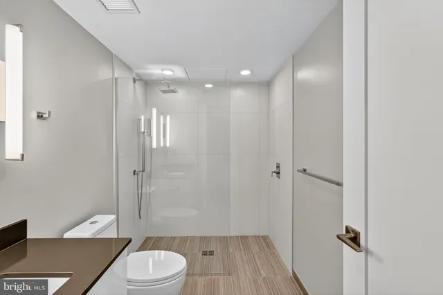 a bathroom with a granite countertop bathtub shower sink mirror vanity and toilet