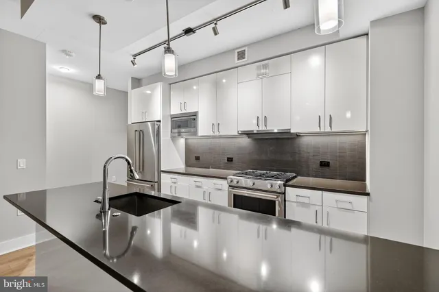 a kitchen with stainless steel appliances granite countertop a sink a stove and a refrigerator