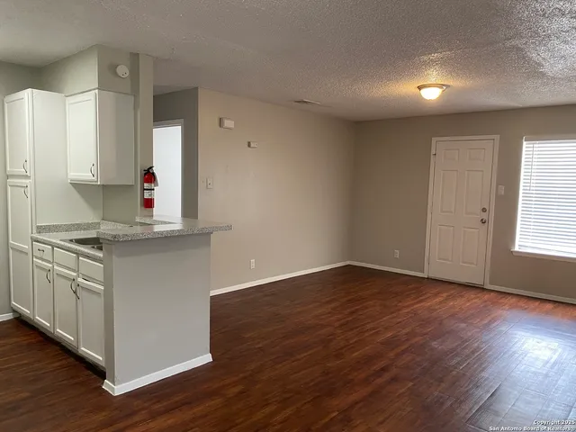 a kitchen with granite countertop wooden floors and white cabinets