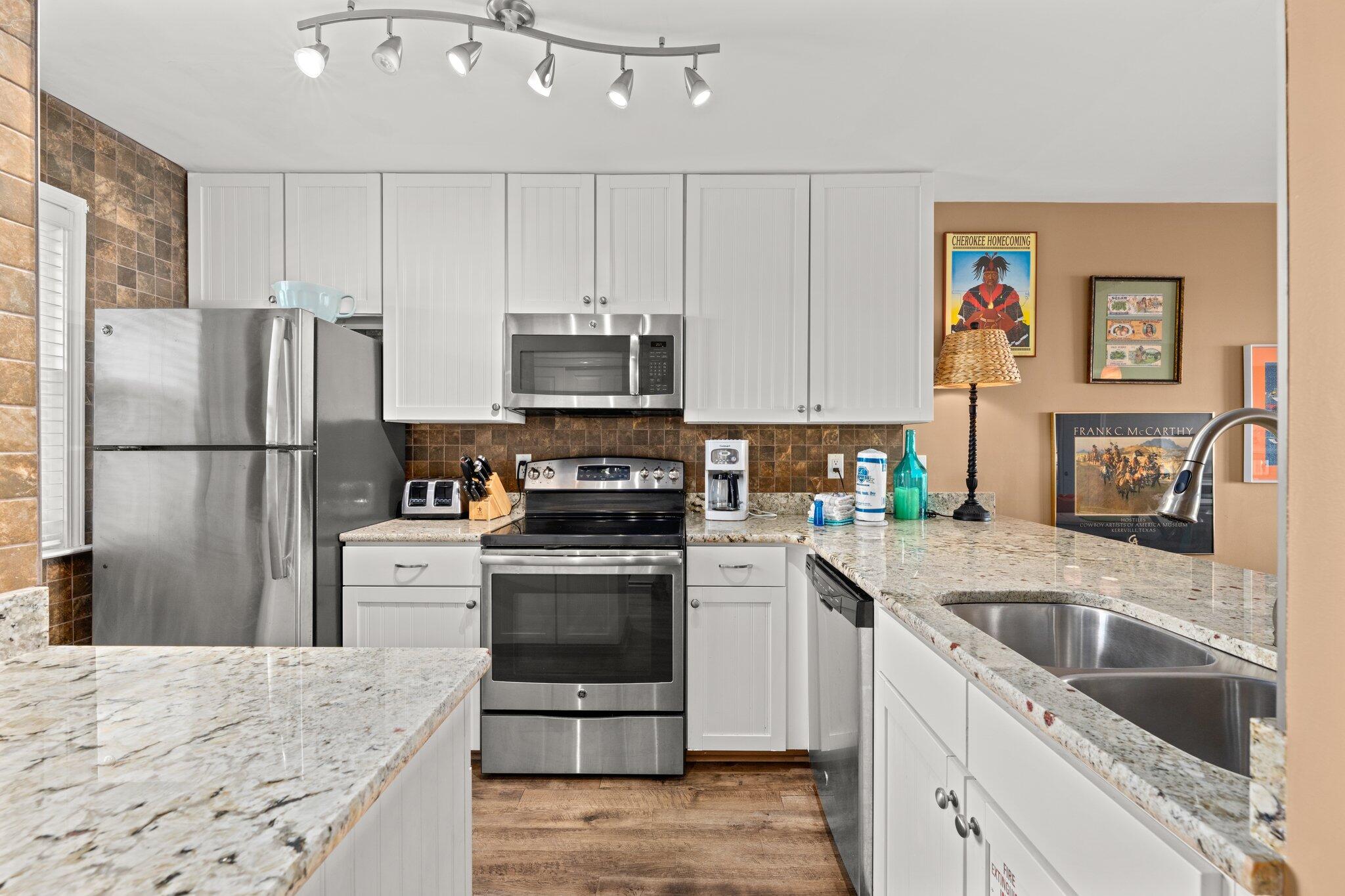 23011 Front Beach Road, Unit F7 Panama City Beach, FL 32413 - Photo 11 of 31 a kitchen with kitchen island granite countertop a refrigerator stove and sink