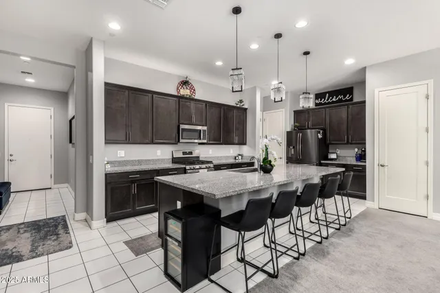 a kitchen with stainless steel appliances kitchen island granite countertop a stove a refrigerator a oven a sink a dining table and chairs