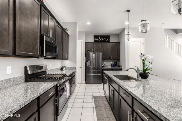 a kitchen with granite countertop stainless steel appliances a sink stove top oven and refrigerator