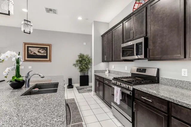 a kitchen with granite countertop a stove a sink and a microwave