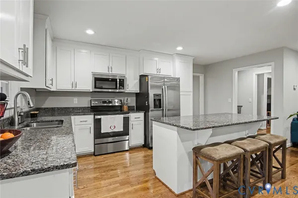 a kitchen with stainless steel appliances granite countertop a sink stove microwave and refrigerator