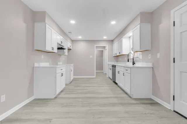 a large white kitchen with kitchen island a sink a center island stainless steel appliances and a window