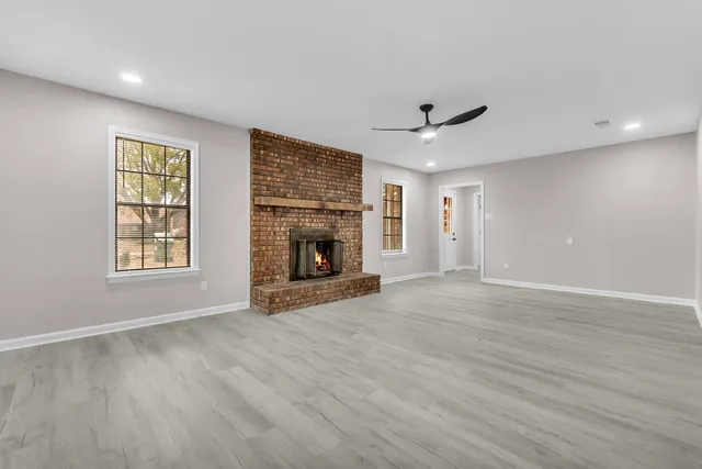 an empty room with windows and fireplace