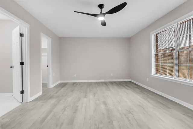 a view of empty room with wooden floor and fan