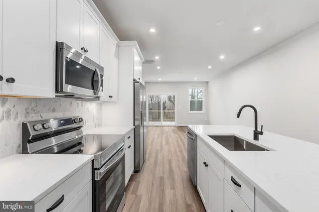 a kitchen with stainless steel appliances granite countertop a sink and stove top oven with wooden floors