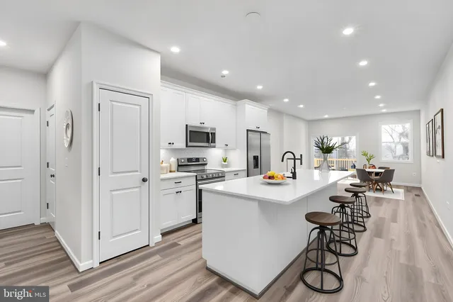 a kitchen with stainless steel appliances a sink a stove a refrigerator cabinets and living room view