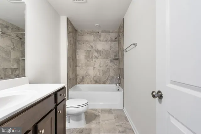 a bathroom with a bathtub shower sink vanity and a toilet