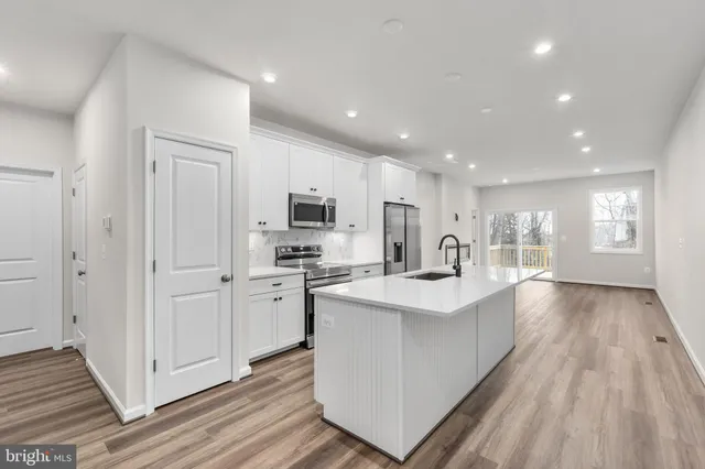 a large white kitchen with stainless steel appliances granite countertop a lot of counter space and wooden floors