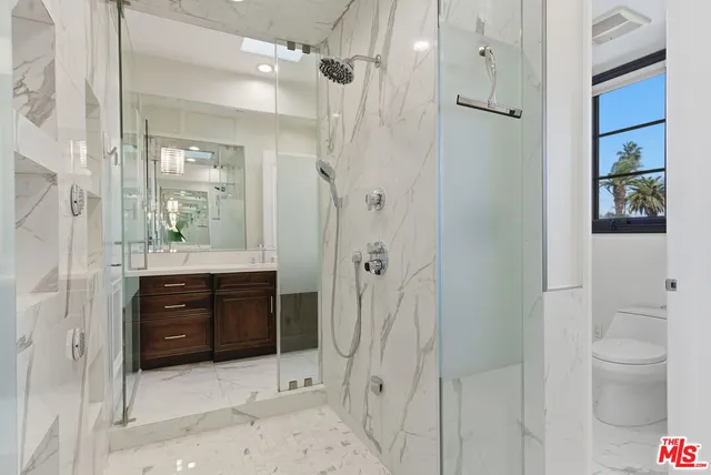 a bathroom with a granite countertop sink a toilet and shower