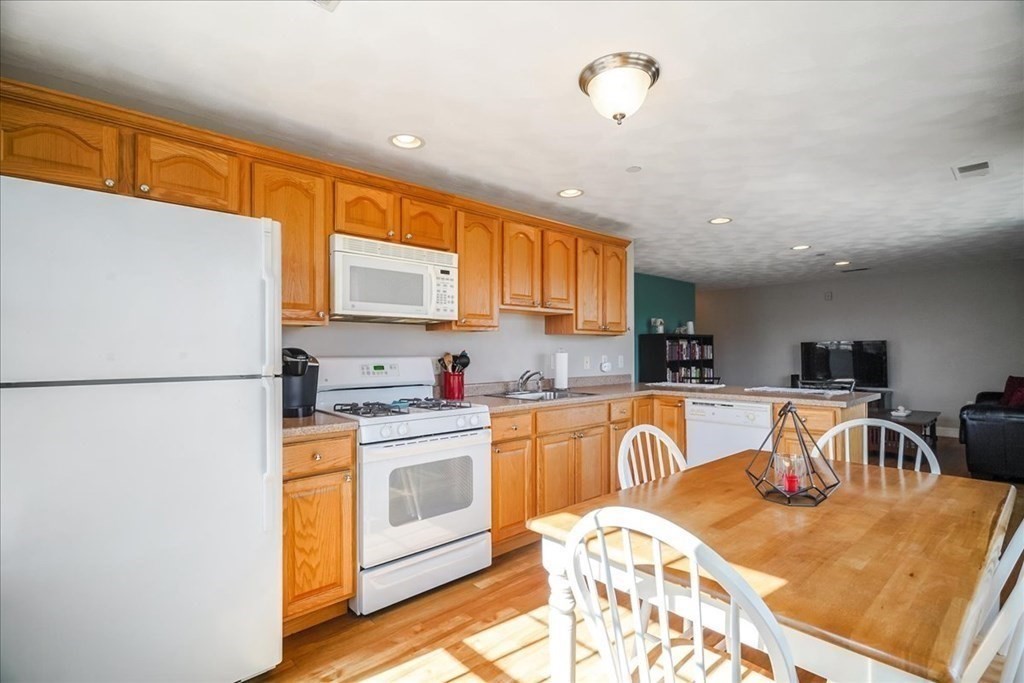 103 Elliott Street, Unit 12 Beverly, MA 01915 - Photo 11 of 25 a kitchen with stainless steel appliances granite countertop a refrigerator a stove top oven a sink dishwasher and white cabinets with wooden floor