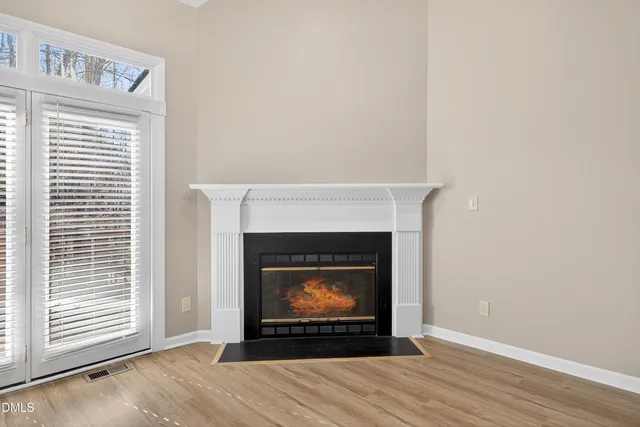 a view of an empty room with wooden floor and windows