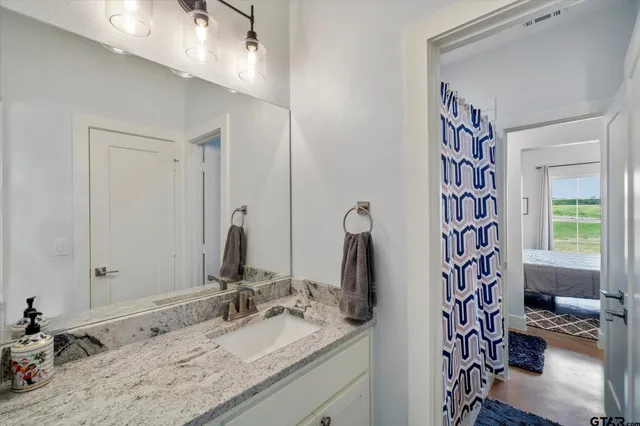 a bathroom with a granite countertop sink and a mirror