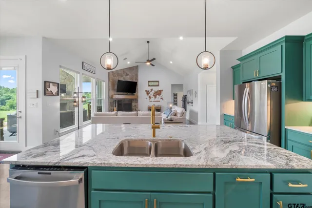a kitchen with kitchen island granite countertop a sink a counter space cabinets and stainless steel appliances