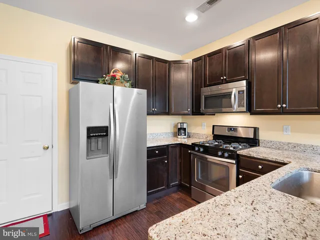 a kitchen with granite countertop a refrigerator and a stove top oven