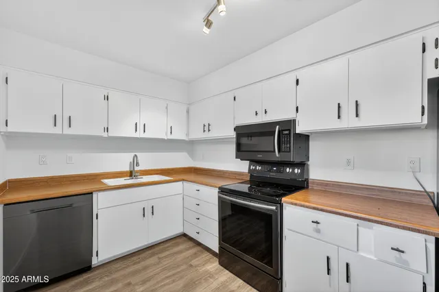 a kitchen with cabinets stainless steel appliances a sink and wooden floor