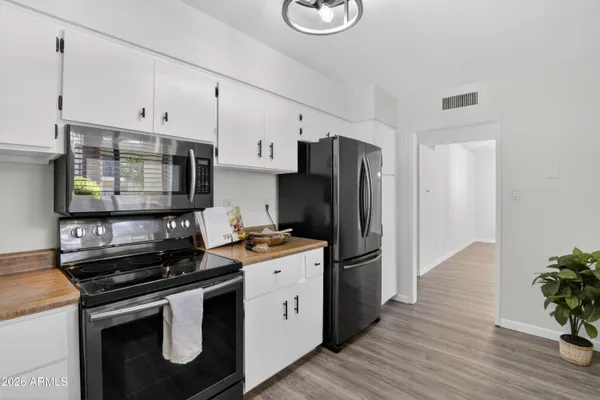 a kitchen with stainless steel appliances a refrigerator a sink and white cabinets