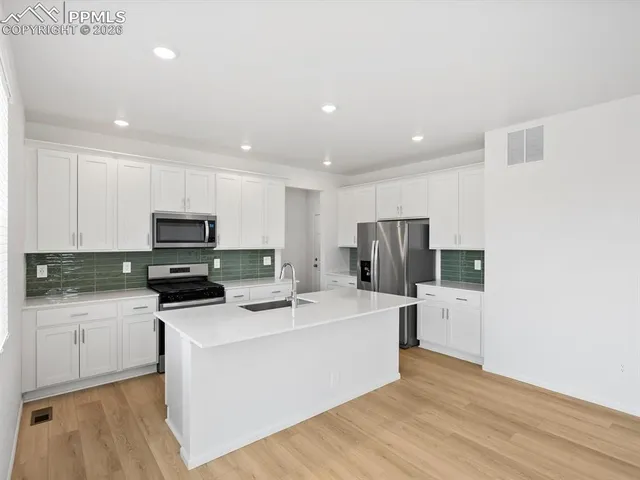 a kitchen with stainless steel appliances a refrigerator a sink a stove a microwave and cabinets