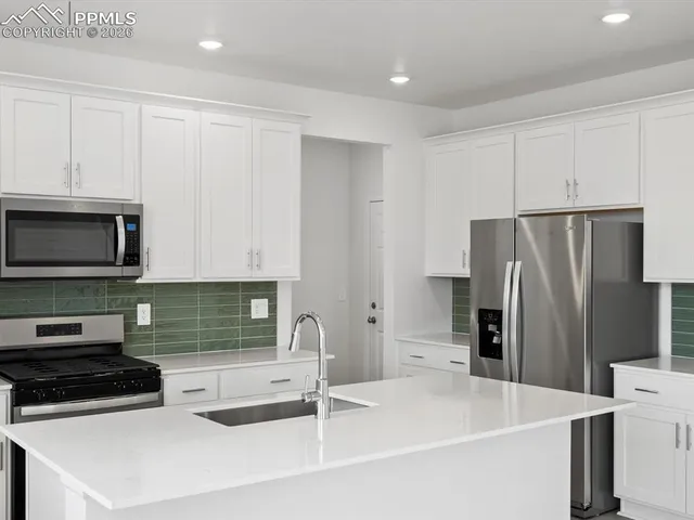 a kitchen with granite countertop white cabinets stainless steel appliances and a sink