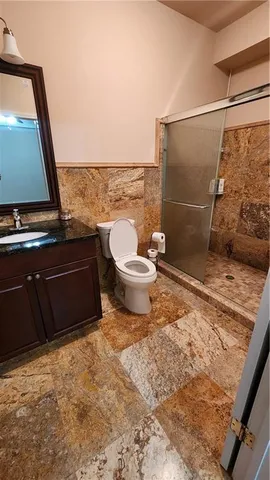 a bathroom with a granite countertop sink and a toilet
