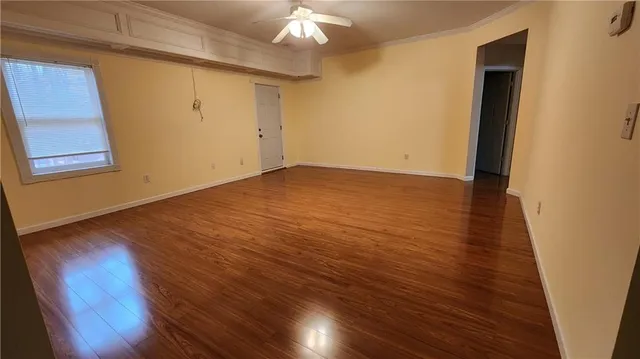 a view of an empty room with wooden floor and a window