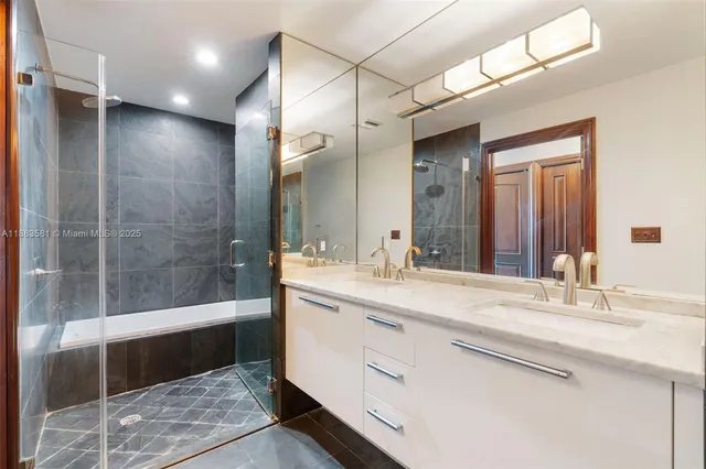 a bathroom with a sink double vanity granite tub shower and a mirror
