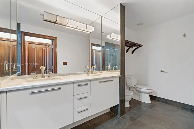 a bathroom with a toilet a double vanity sink and a mirror