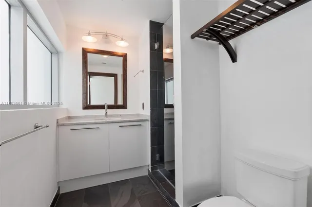 a bathroom with a granite countertop sink mirror and toilet