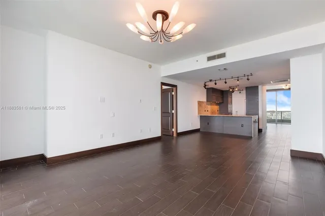 a view of empty room with wooden floor and a window
