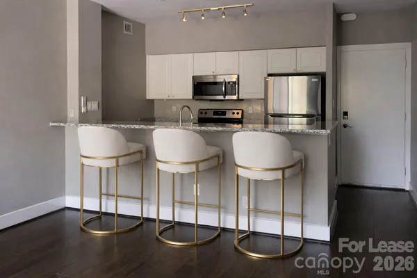 a kitchen with stainless steel appliances granite countertop a stove a refrigerator and a chair