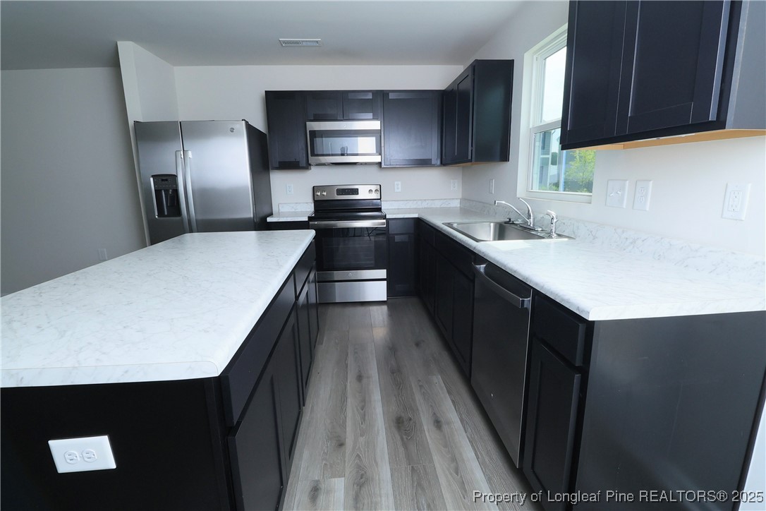 96 Cutty Way Lillington, NC 27546 - Photo 12 of 37 a kitchen with kitchen island a sink dishwasher a stove and refrigerator with wooden floor