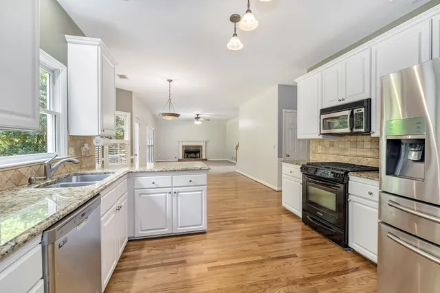 a large kitchen with granite countertop a stove top oven a sink dishwasher a dining table and chairs with wooden floor