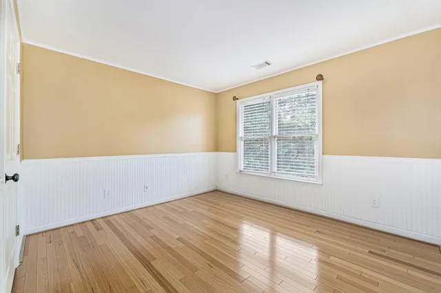 a view of an empty room with wooden floor and a window