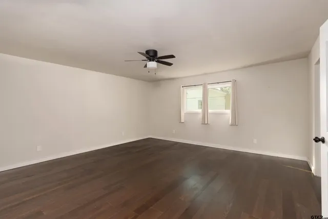 a view of an empty room with a window and wooden floor