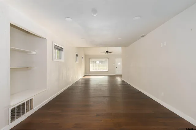 a view of an empty room with wooden floor and a window