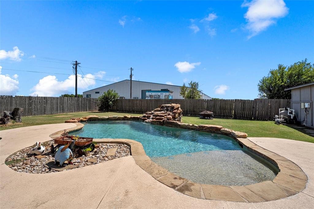 3696 Old Lorena Road Lorena, TX 76655 - Photo 24 of 27 Freeform swimming pool featuring a rock waterfall, flagstone coping, and a surrounding concrete patio