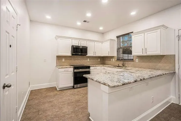 a kitchen with stainless steel appliances granite countertop a stove a sink and a microwave