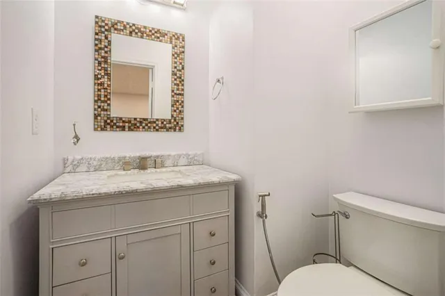 a bathroom with a granite countertop toilet sink and mirror