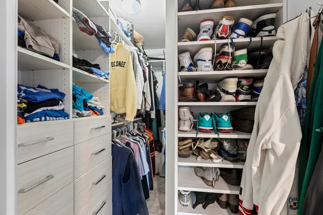 a view of walk in closet with clothes and shoes