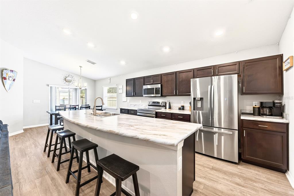 6348 Gardner Road Lakeland, FL 33813 - Photo 10 of 26 a kitchen with stainless steel appliances granite countertop a refrigerator a stove a sink a dining table and chairs