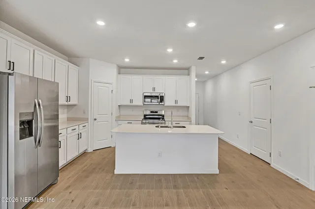 a large kitchen with stainless steel appliances a large counter top and a refrigerator