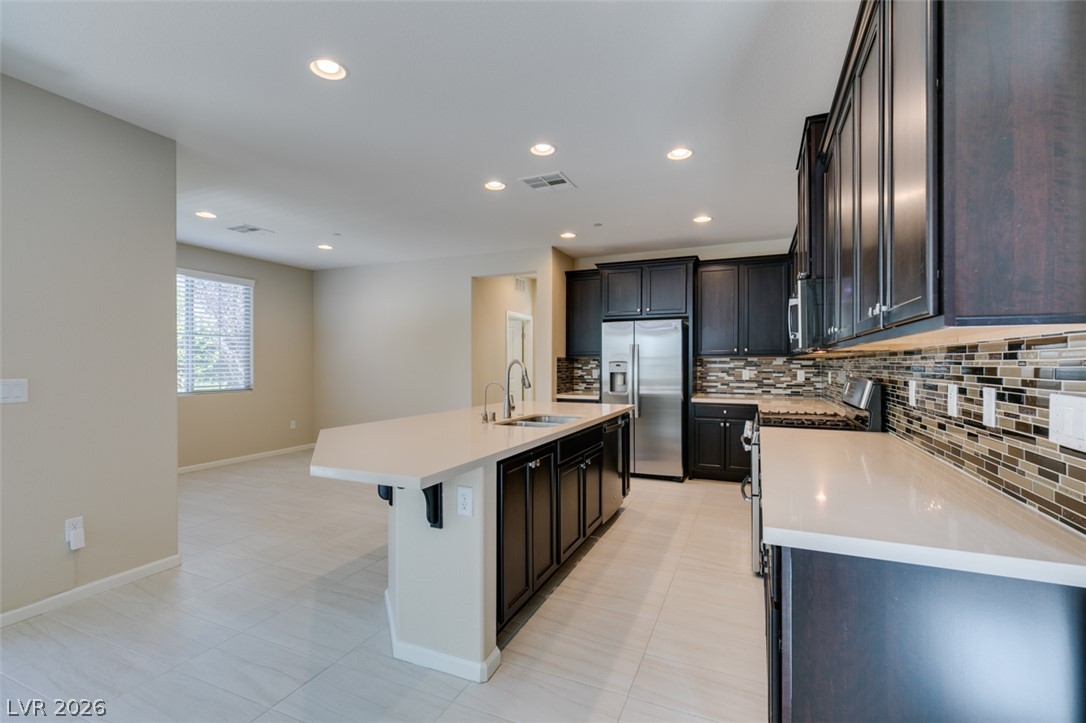 2549 Sable Ridge Street Henderson, NV 89044 - Photo 29 of 48 Modern kitchen with sleek dark cabinetry, an extended island, and contemporary backsplash.