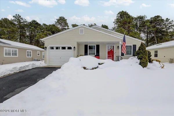 a front view of house with yard and trees in the background