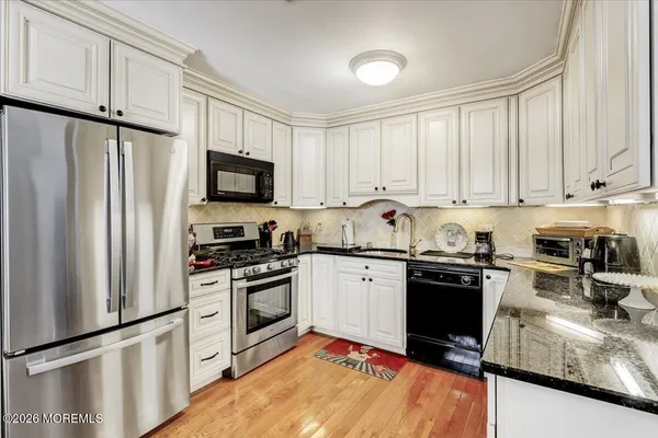 a kitchen with granite countertop a refrigerator stove top oven and sink