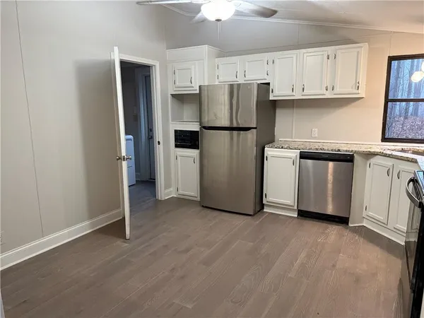 a kitchen with stainless steel appliances granite countertop a refrigerator sink and white cabinets