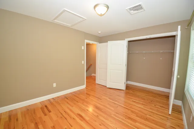 an empty room with wooden floor and closet